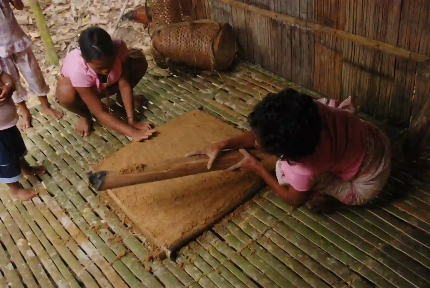 Two Semai women pound earth on a new fire mound